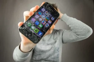 Homem segurando um iphone quebrado para conserto